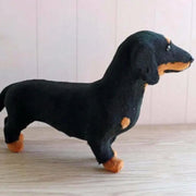 Plush toy dachshund on a wooden floor with a white wall background